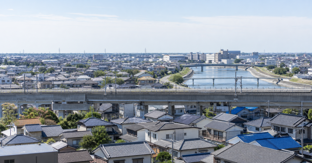 高架鉄道と川を含む平坦な住宅都市の街並み(越谷市の低平地と住宅ストックが建設業の受注基盤になる地域事情のイメージ)